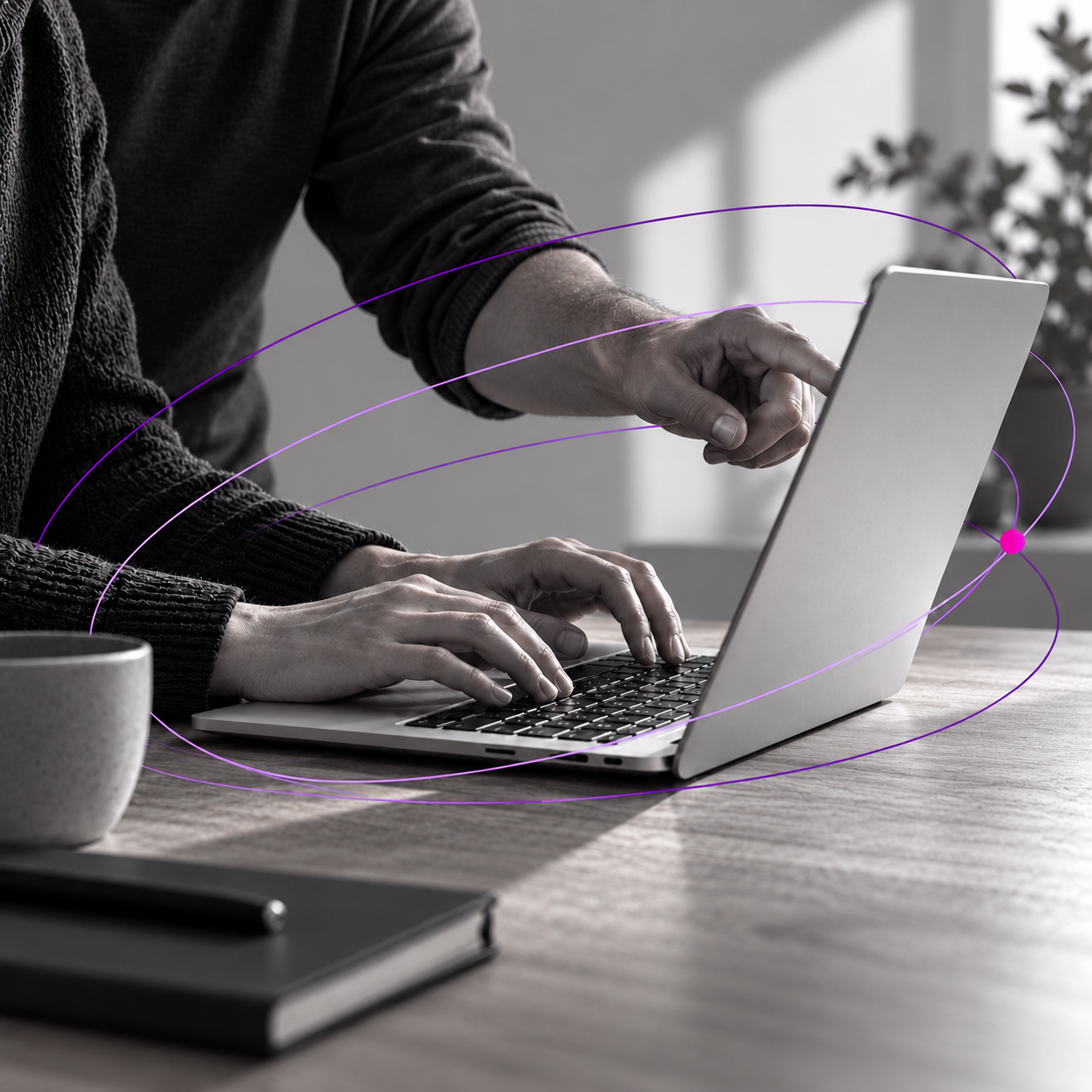 Hands working on a laptop encircled by purple orbital lines